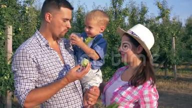 家庭关系，快乐的父母在果园吃水果，小儿子喝新鲜果汁