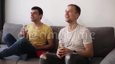 两个兴奋的成年男子喝啤酒，在电视上观看室内足球比赛。 庆祝胜利。 关门