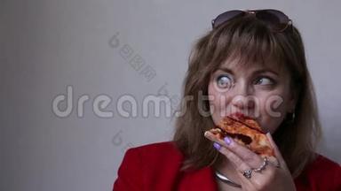 一个成熟的女人，嘴唇鲜红，吃着披萨。 有害食物