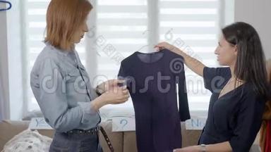两个漂亮的年轻女人正在从事衣柜的分析。 女朋友选择服装并挑选图片。