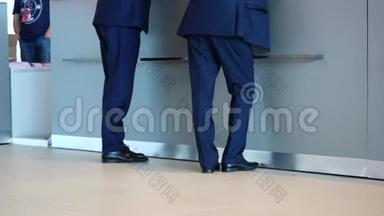 两个穿着蓝色裤子、西装外套和黑色鞋子的商人站在<strong>接待处</strong>询问