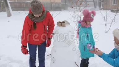 户外冬<strong>季家</strong>庭游戏。 妈妈和两个女儿一起塑<strong>造</strong>了雪人。