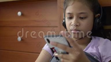 小亚洲女孩使用手机耳机和<strong>观看视频</strong>。