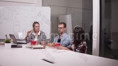 年轻的白种人<strong>同事</strong>午休时<strong>一起</strong>在办公室吃披萨。 笑，说话，玩得开心。 工作人员