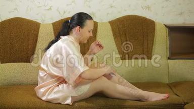 沙发上的一位年轻女士脱毛后将滑石粉涂在腿上
