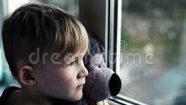 小男孩微笑<strong>着看着窗外</strong>。 下雨天，小孩从窗户往外<strong>看</strong>