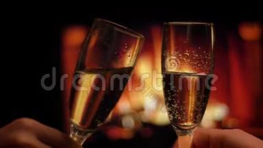 亲密拍摄两只手的朋友，在温暖的壁炉旁，手里拿着装满香槟的酒杯，在室内令人寒心