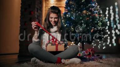 一个漂亮的女孩正在一个装饰得很好的客厅里打开一个坐在地板上的圣诞礼物。
