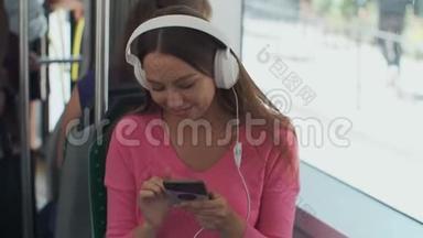 坐在<strong>公共交通工具</strong>上享受旅行的年轻女乘客，戴着耳机坐在现代有轨电车的车窗旁。