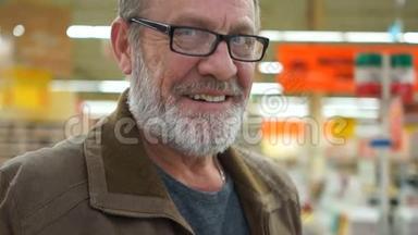 一个戴着黑边眼镜的灰胡子男子的肖像。 张开的微笑，看得见的牙齿，直视的蓝眼睛