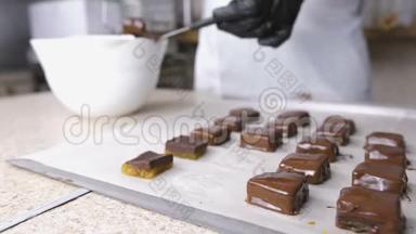 贝克`手把糖果浸在融化的巧克力里。 巧克力糖果的生产。