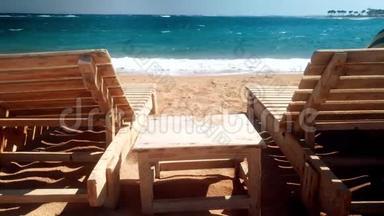 海滩上两个木制日光浴床的4K视频。 汹涌的海浪<strong>席卷</strong>海岸