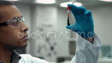 年轻的男科学家在实验室检查一个装满血液的试管
