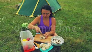 帐篷附近的一个林间空地上，一个女<strong>人</strong>在树桩上剪了一个<strong>蘑菇蘑菇蘑菇</strong>，作为一张桌子。