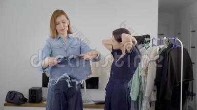 两个漂亮的年轻女人正在从事衣柜的分析。 女朋友选择服装并挑选图片。