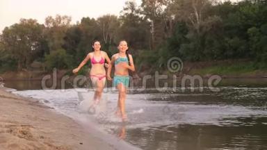 女孩们在沙滩上奔跑，在海滩上溅起水滴，笑着。 快乐自由的青少年
