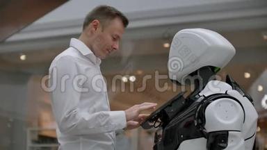 购物中心的那个人和一个机器人顾问沟通。 现代商店和机器人销售商。 机器人帮助一个男人