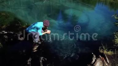 一位戴着背包帽子的年轻游客正在从冰冷的<strong>蓝山</strong>湖喝水