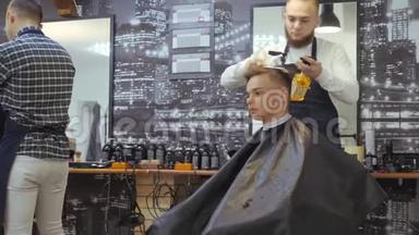 男士美容师。 理发店。 一个年轻人从一个头发被绑在头上的留着胡子的男人那里得到理发和头发护理
