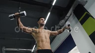 一个年轻的运动员在健身房里用哑铃抽胳膊肌肉。