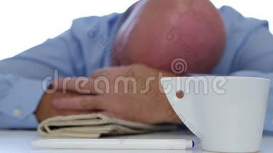 疲惫的商人用咖啡和报纸在桌上打盹