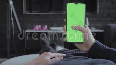 绿色屏幕-一个男人在客厅里看着一部智能手机，然后刷卡