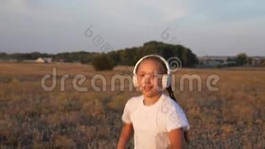 年轻的运动女孩戴着耳机慢跑，一个年轻女孩在日落时训练，听音乐