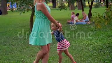 年轻的<strong>一家人</strong>夏天在公园散步，<strong>女儿</strong>正在和妈妈玩轮番游戏
