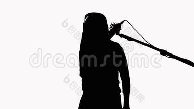 一个长发女孩的剪影，她对着录音棚的麦克风唱歌。在白色背景上。<strong>录制音乐</strong>视频