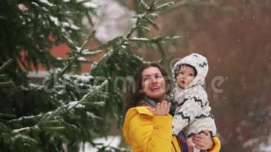 母子对杉树附近公园里的第一场雪很佩服.. 那个女孩穿着一件黄色的<strong>羽绒服</strong>，孩子