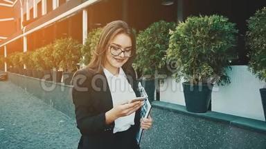 年轻漂亮聪明的商务女孩穿着商务服走路。 在这段时间里，她拿着一个文件夹