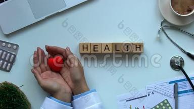 健康单词：桌子上的木立方体，医生拿着玩具心脏，<strong>捐献</strong>者