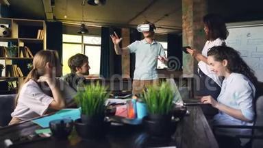 年轻人在现代办公室里使用虚拟现实眼镜，他的同事正在使用平板电脑和笔记本电脑