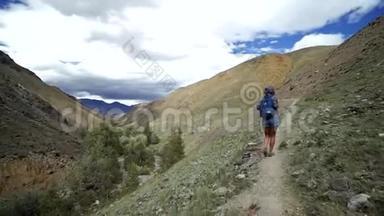 旅行者女孩爬上石山。 天空和山的背景都是云