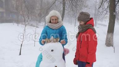 妈妈和两个女儿一起塑<strong>造</strong>了雪人。 户外冬<strong>季家</strong>庭游戏。