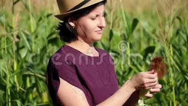 一个女农民站在玉米地里，检查收获的质量。 农业和收获的概念..