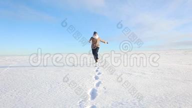 一个年轻的女孩<strong>欢快</strong>地走着，跳上一片白雪覆盖的<strong>田野</strong>。 冬天阳光明媚的欢乐景象，有一条路和一片雪域