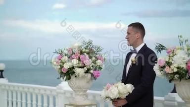 婚礼上的年轻新郎站在拱门的祭坛前等待新娘。 海边的婚礼