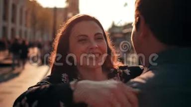 迷人的黑发女人，满脸雀斑的跑过来拥抱她的男朋友在城市街道。 看镜头