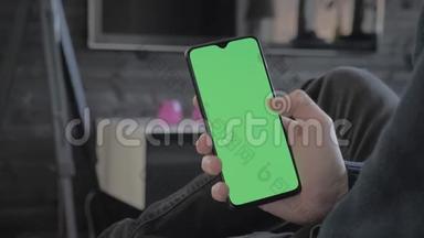 绿色屏幕-一个男人在客厅里看着一部智能手机，然后刷卡
