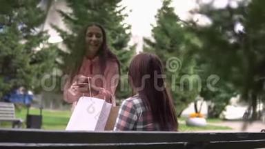 购物后的女孩跑到她的朋友面前，在包裹里展示她的购物。 慢动作。