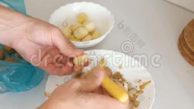 男人`手在用黄色的剥皮机剥土豆。