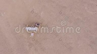 年轻的赤脚女人坐在沙漠里，靠近一架白色的钢琴。 从上面看。 超真实的故事<strong>情节</strong>。 空中观景。