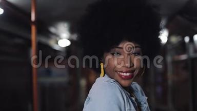 非裔美国妇女看着相机微笑着站在公共交通工具，stealicam拍摄。 特写