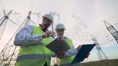 电工男女讨论电力线路附近的电气设备。