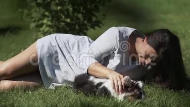 一个留着长发的小女孩在草地上的公园里和一只小狗玩耍，白天在阳光下心情很好