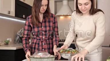 两个年轻女孩把鸡肉放在烤包里。 美味的鸡肉晚餐