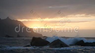 在加那利群岛的特内里费，美丽的日落光线下，海浪在空中升起。 一股巨浪冲过来