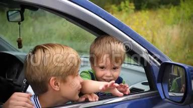 两个孩子坐在车里。 兄弟俩<strong>看着窗外</strong>微笑。 快乐的童年
