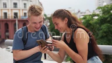 年轻的幸福夫妇看着智能手机屏幕，笑着看着华尔街